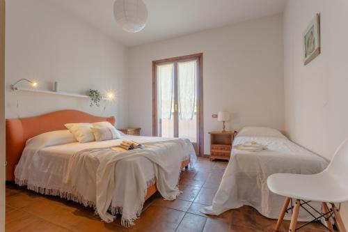 1 dormitorio blanco con 2 camas y ventana en Villa Rosè - Natura vista mare - Narramondo Villas en Cologna