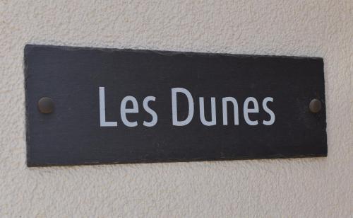 a sign with the words less dances on a wall at Les Dunes in Camber