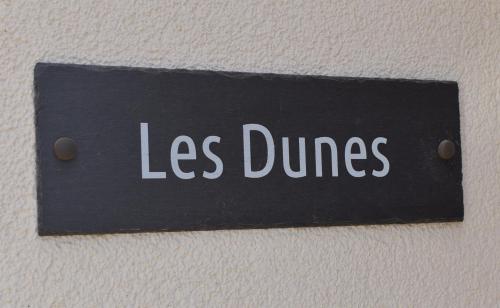 ein Zeichen mit den Worten weniger Tänze an der Wand in der Unterkunft Les Dunes in Camber