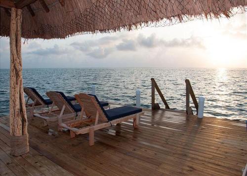 a group of chairs and a table on a wooden deck at Laura's Lookout in Caye Caulker