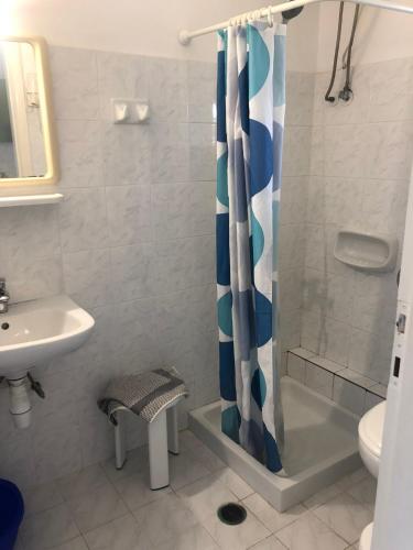 a bathroom with a shower with a blue and white shower curtain at Eleftheria Studios and Apartments in Acharavi