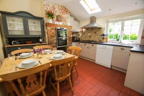 a kitchen with a wooden table and chairs in it at Beeches Cottage - Beautiful Garden - Parking in Handcross