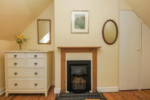 a room with a fireplace and a dresser and a mirror at Beeches Cottage - Beautiful Garden - Parking in Handcross