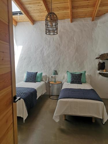 two beds in a room with wooden ceilings at Villa Los Volcanes in Lajares