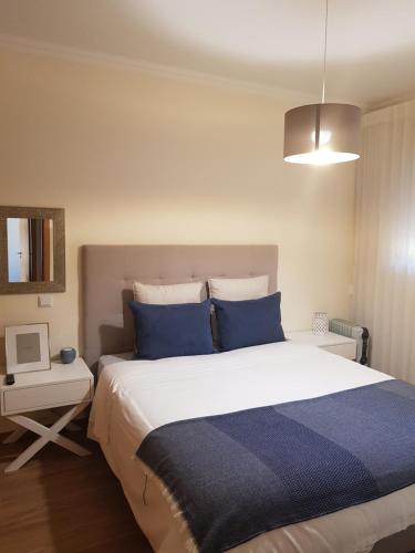 una camera da letto con un grande letto con cuscini blu di JARDINS DA MARINA APARTMENT Ai ad Albufeira