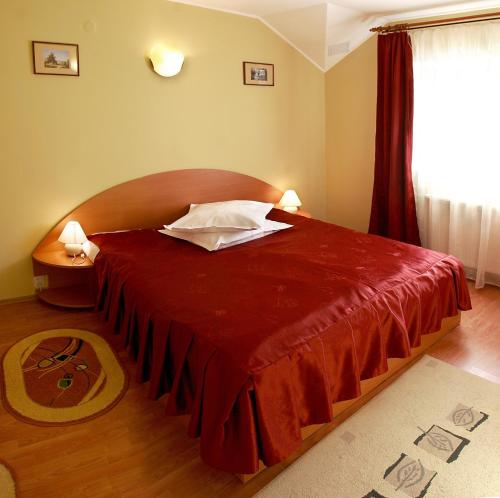 a bedroom with a large bed with a red bedspread at Hotel Riviera in Sinaia