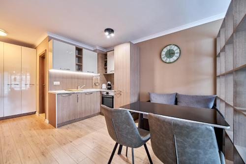 a kitchen with a table and chairs and a clock on the wall at Comfy luxury center apartment in Varna City
