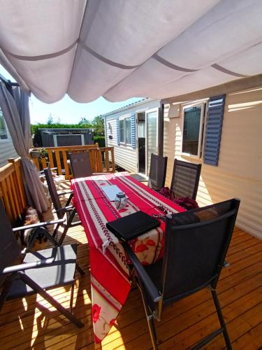 - une table et des chaises sur la terrasse d'une maison dans l'établissement La Chanterie Agréable Mobil-Home Résidentiel Normand, à Saint-Pair-sur-Mer