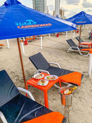 a beach with chairs and a table with food on it at Hotel Cabreromar in Cartagena de Indias
