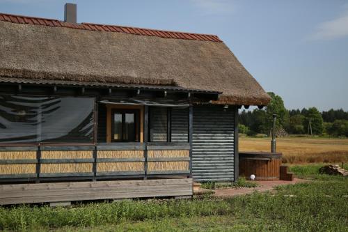 uma casa antiga com um telhado de palha e uma janela em Brīvdienu māja Pakavi em Skulte