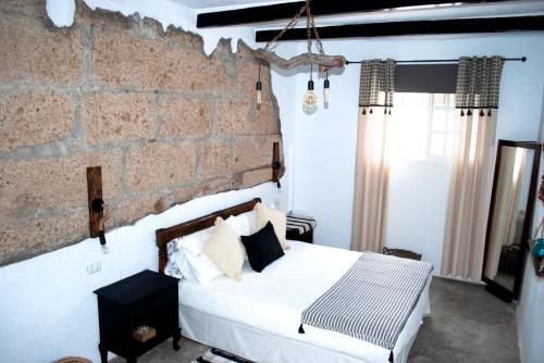 - une chambre avec un lit et un mur en briques dans l'établissement Casa el escaño, à Granadilla de Abona