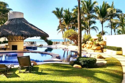 een zwembad in een resort met palmbomen en de oceaan bij Depa de lujo en Acapulco diamante sin daños por huracán Otis-Precio especial in Acapulco