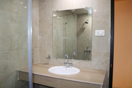un baño con lavabo y espejo en Hotel Centro, en Calangute