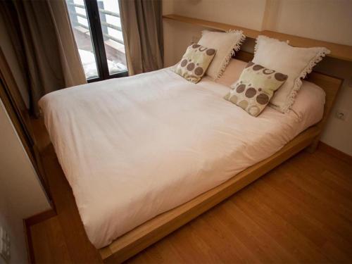 a bed with white sheets and pillows and a window at Apartamentos Boabdil in Sierra Nevada