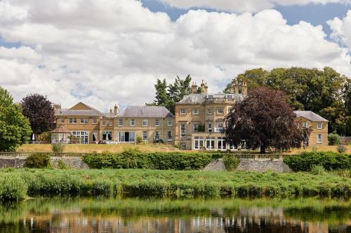 a large house next to a body of water at Ednam House Hotel in Kelso