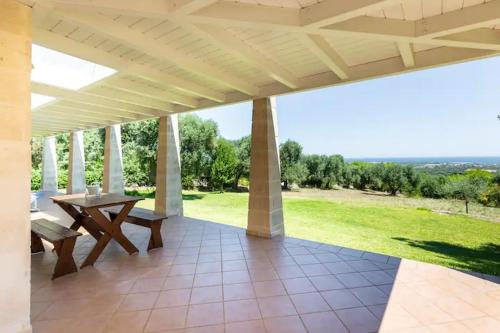 eine Terrasse mit einem Tisch und einer Bank auf einem Feld in der Unterkunft Villa Alerika in Carovigno