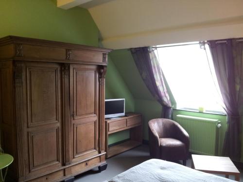 - une chambre avec une grande armoire en bois et une télévision dans l'établissement New-Castle, à Spa