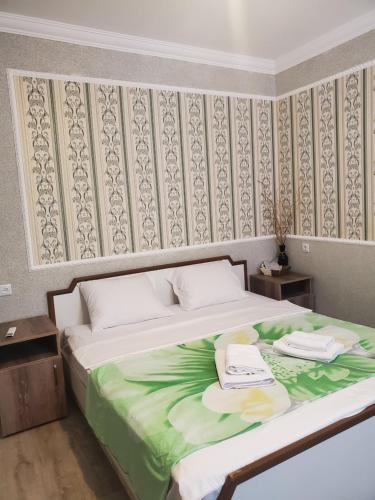 a bedroom with a large bed with a green blanket at Beehives in Kutaisi