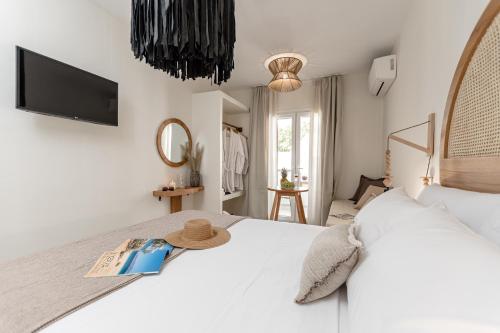 a bedroom with a white bed with a hat on it at Heavenly Suites & Studios in Naxos Chora