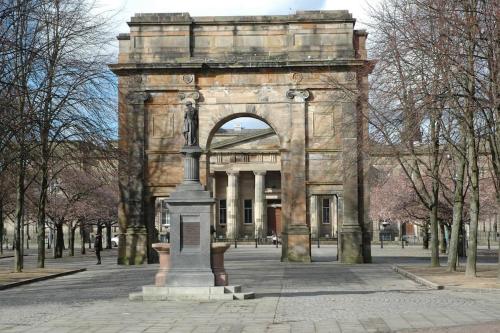duży kamienny budynek z łukiem w parku w obiekcie The Nelson - Spacious City Property and Free Parking w Glasgow