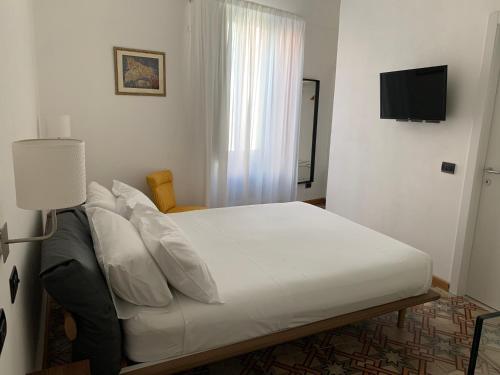 a bedroom with a bed with white sheets and a television at AMECASA in Noto