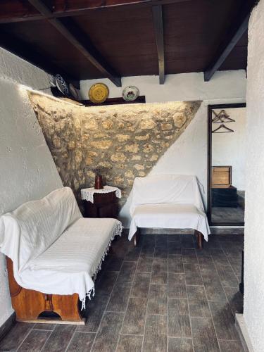 a room with two white beds and a wall at Lindia Athena Traditional House in Karpathos