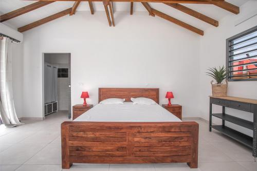 a bedroom with a large wooden bed and two night stands at Bungalow Pom 1, piscine, à 5 min des plages in Le Vauclin