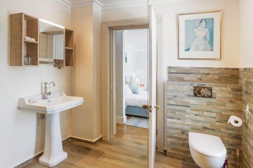 a bathroom with a sink and a toilet and a bedroom at Villa Bianca B & B in Cape Town