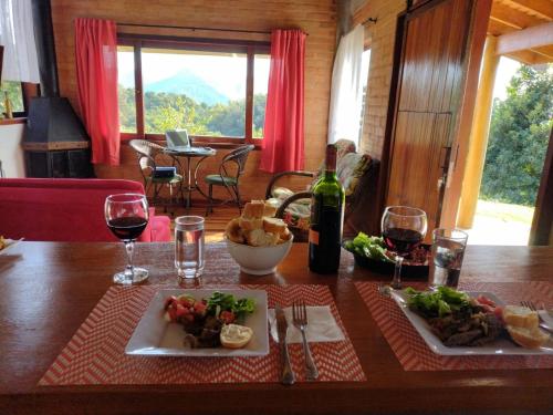 a table with two plates of food and wine glasses at CASA NA MONTANHA in Gonçalves