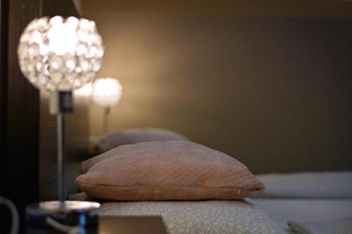 a pillow sitting on a bed next to a lamp at R.Gold Apartman in Makó