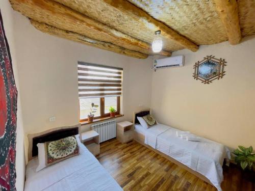 a living room with two beds and a window at Hotel Mohina in Samarkand