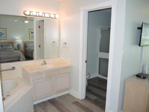 ein Badezimmer mit einem Waschbecken, einer Badewanne und einem Spiegel in der Unterkunft 503L villa in Calabash