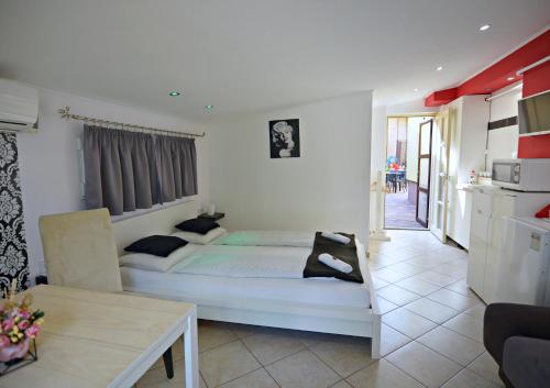 a white bedroom with a bed and a table at R.Gold Apartman in Makó