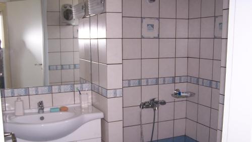een wit betegelde badkamer met een wastafel en een spiegel bij KomiVillas in Lilikás