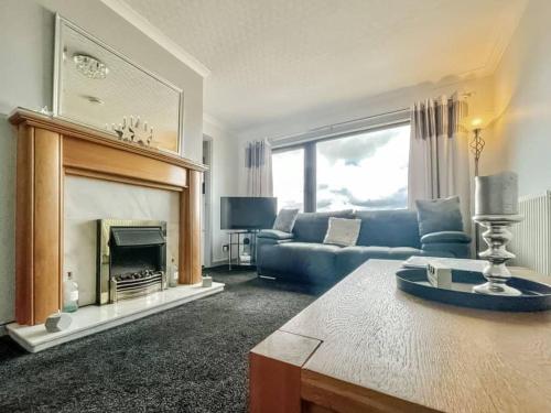 a living room with a blue couch and a fireplace at BAYVIEW in Stornoway