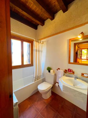 a bathroom with a toilet and a tub and a sink at HOTEL RURAL LA HUERTA in Montejo de la Vega de la Serrezuela
