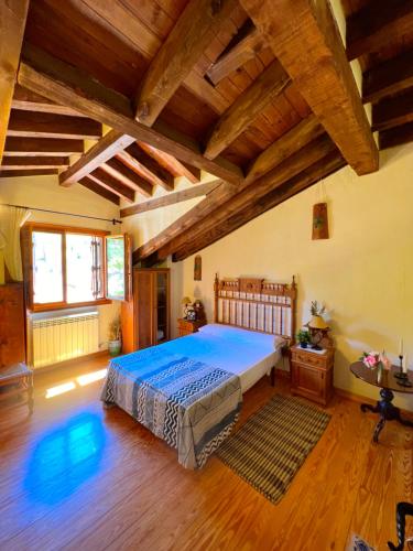 ein Schlafzimmer mit einem großen Bett in einem Zimmer mit Holzdecken in der Unterkunft HOTEL RURAL LA HUERTA in Montejo de la Vega de la Serrezuela