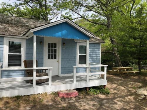 una casita azul con porche en Herring Run Cabins and Inn en Bourne