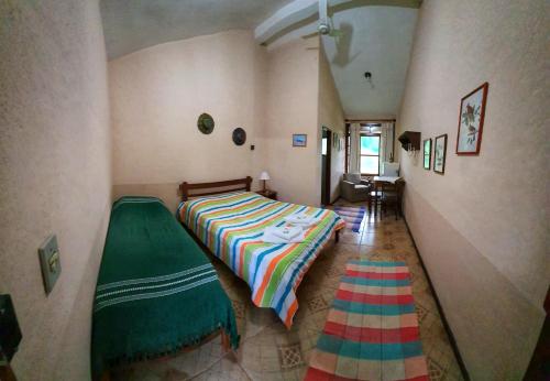 1 dormitorio con 1 cama con una manta colorida en Fazenda Serra que Chora - Pousada e Restaurante, en Itanhandu