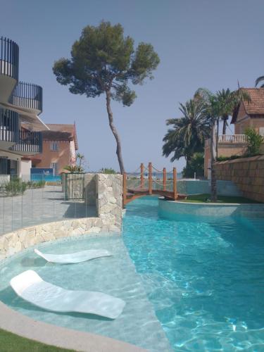 una piscina de agua azul y un árbol en Modern nieuwbouwappartement aan het strand van de Mar Menor in Santiago de la Ribera, en Lo Pagán