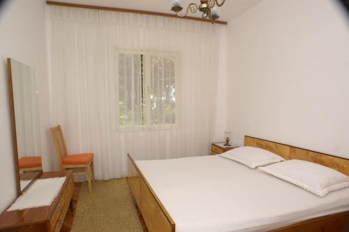 a bedroom with a large white bed and a window at Apartments by the sea Simuni, Pag - 236 in Kolan
