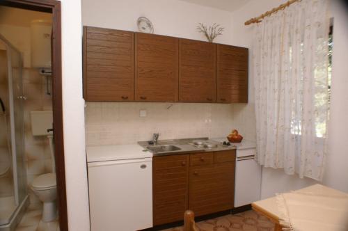 a small kitchen with a sink and wooden cabinets at Apartments by the sea Simuni, Pag - 236 in Kolan