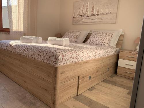 een slaapkamer met een groot houten bed met 2 kussens bij Family friendly apartments with a swimming pool Povljana, Pag - 244 in Povljana