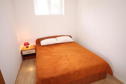 1 dormitorio con 1 cama con manta naranja en Apartment Povljana 224d, en Povljana
