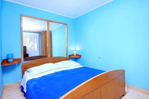 a blue bedroom with a bed and a mirror at Apartments by the sea Brna, Korcula - 171 in Smokvica