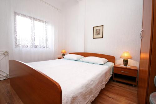 a bedroom with a bed with white sheets and a window at Apartments with swimming pool Pag - 220 in Pag