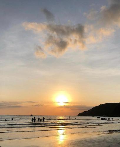 a group of people on the beach at sunset at Residencial Águas de Bare in São Sebastião