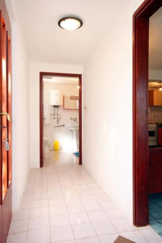 a hallway with a white tile floor and a bathroom at Apartments with parking space Prigradica, Korcula - 193 in Blato