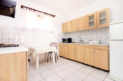 a kitchen with wooden cabinets and a table and a refrigerator at Apartments by the sea Vela Luka, Korcula - 159 in Vela Luka