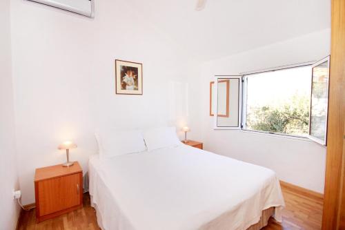 a bedroom with a white bed and a window at Apartments by the sea Kneza, Korcula - 168 in Račišće